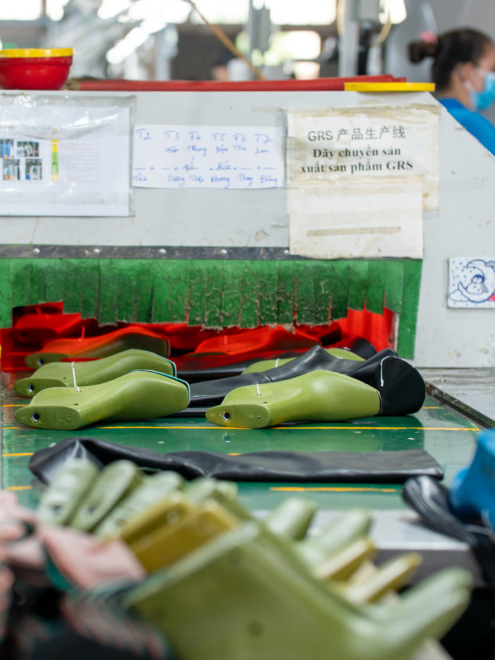 Green shoe lasts and moulded sole samples laid out on a sampling bench on the factory's GRS production line.