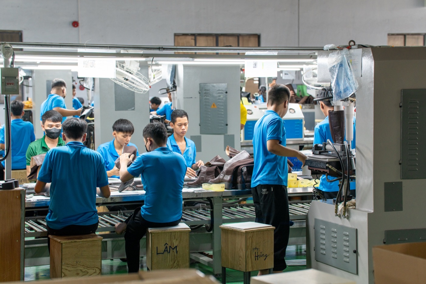 The lasting and finishing line, a team working brown boots along a roller conveyor.