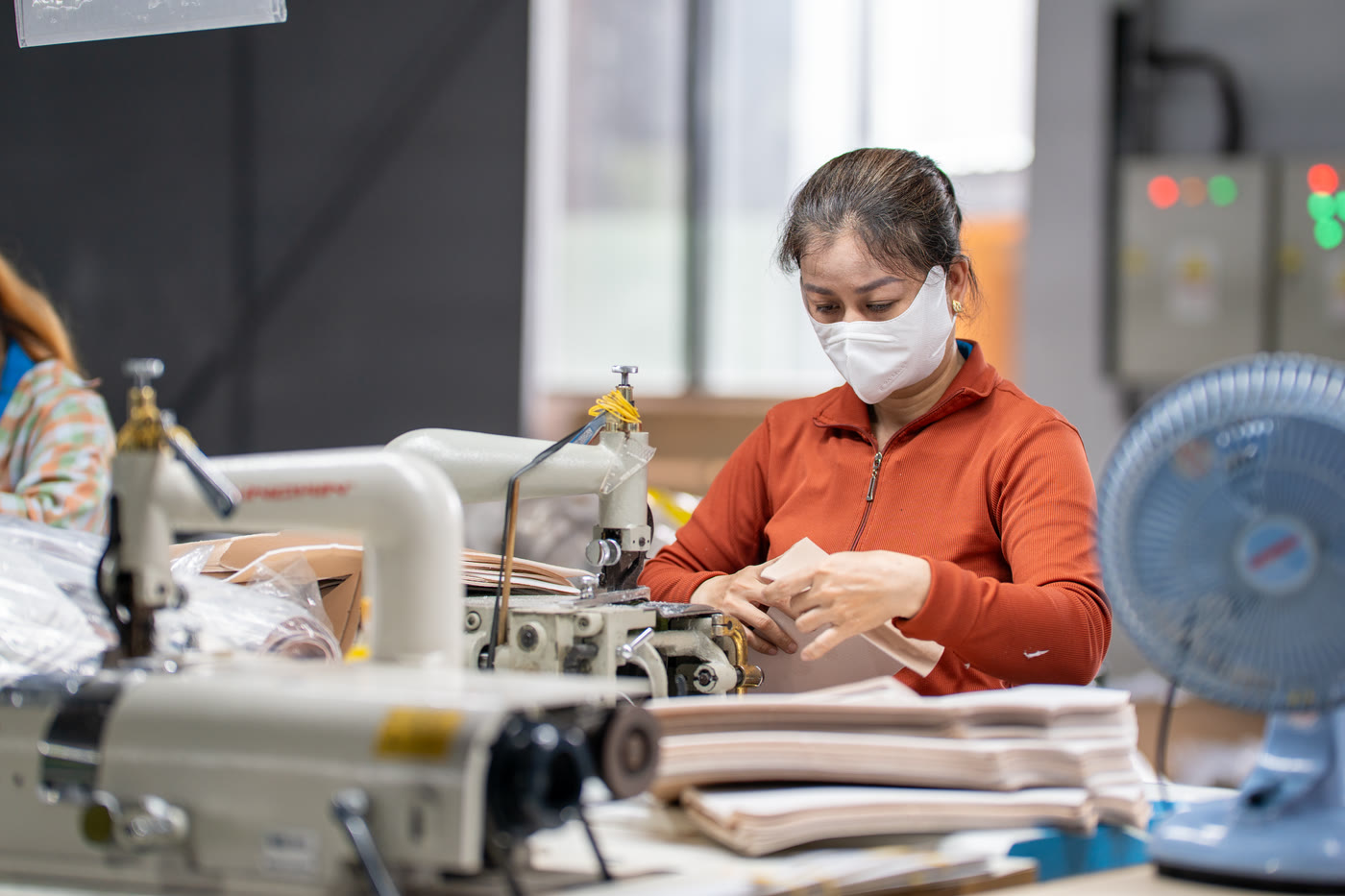 A machinist at a sewing machine, working a pale panel through the needle.