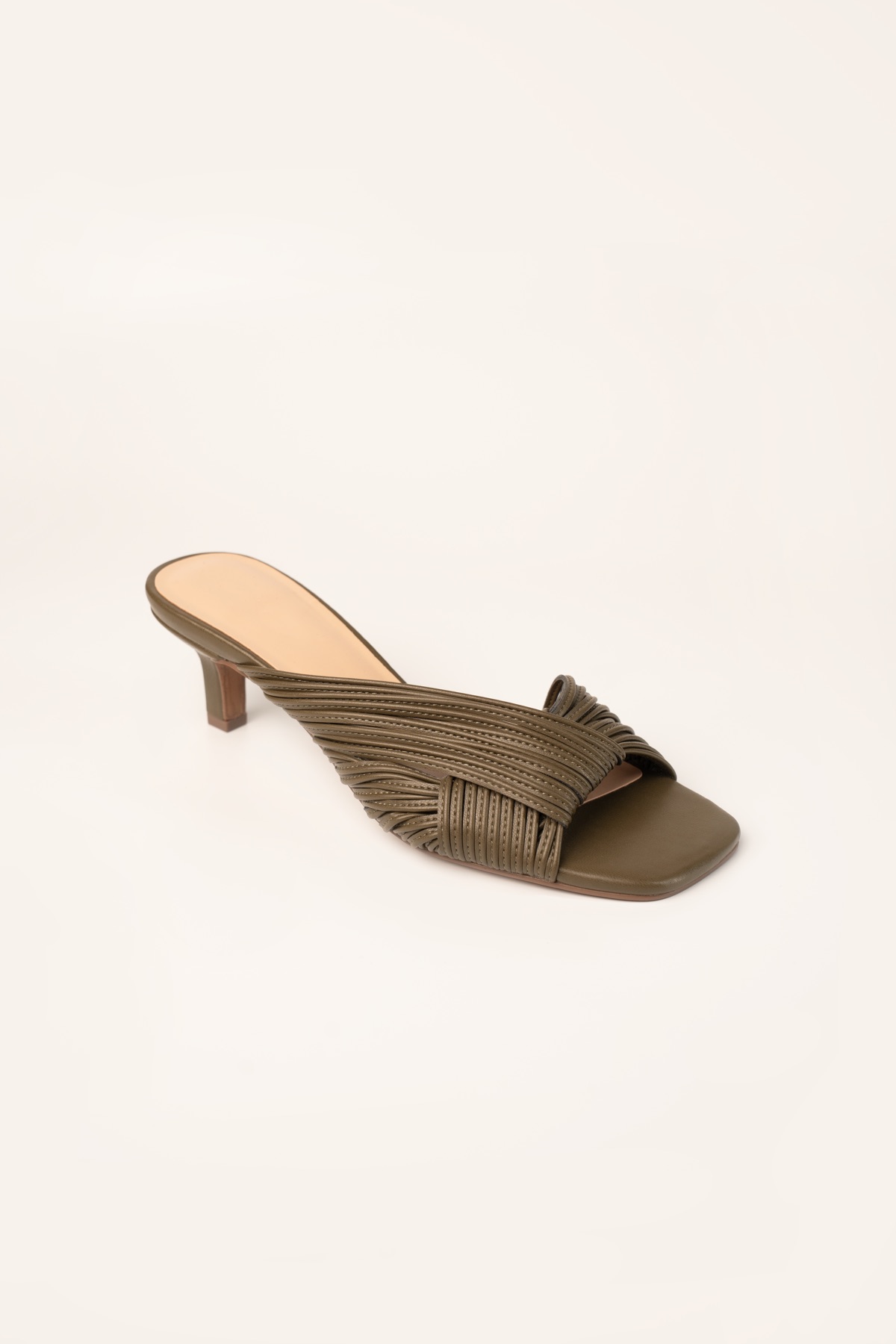 Studio shot of an olive kitten-heel mule with a knotted multi-strand band and square toe.