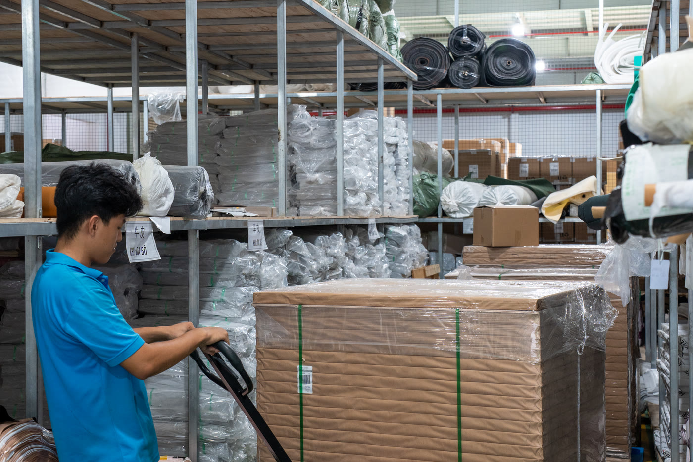 A worker moving a pallet of wrapped cartons through the dispatch store.
