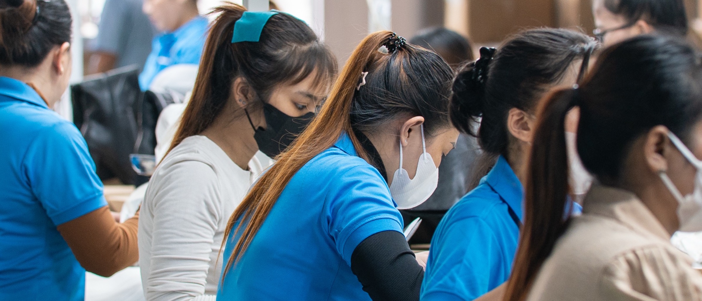 Workers standing shoulder to shoulder at a bench along the production line.