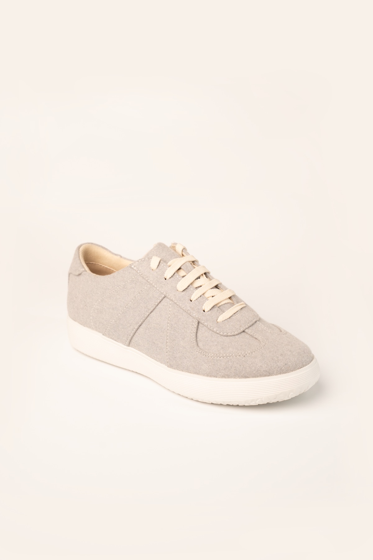 Studio shot of a grey low-top lace-up sneaker with a white cupsole.